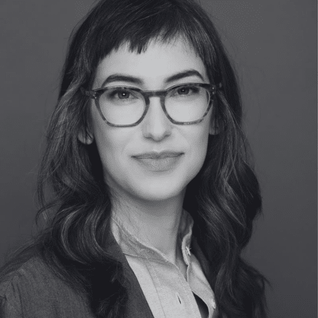Black and white photo of a woman wearing glasses and a blazer.
